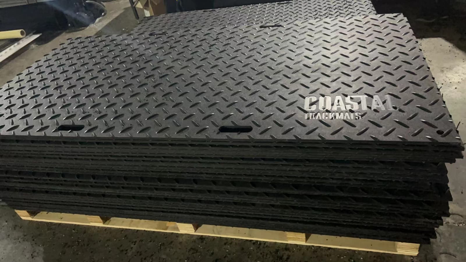 Stack of Coastal Trackmats branded heavy-duty HDPE ground protection mats on pallet ready for delivery in Gold Coast QLD